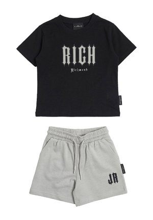 T-shirt corta nera con la scritta "RICH Richmond", abbinata a pantaloncini elasticizzati grigio chiaro con le iniziali "JR" sulla gamba sinistra.