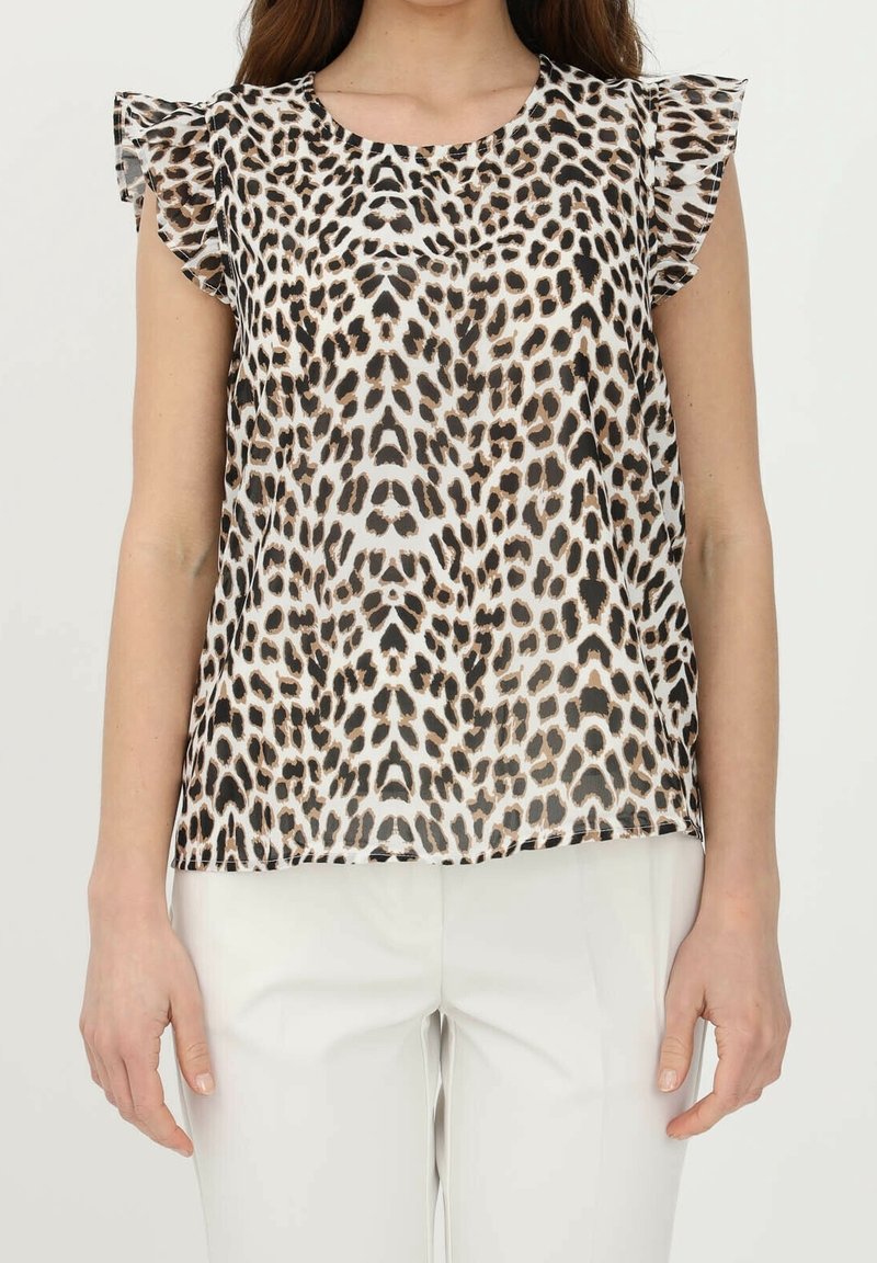 Blusa con stampa leopardata e maniche corte arricciate, in tessuto trasparente con macchie marroni e nere su sfondo chiaro, abbinata a pantaloni bianchi.