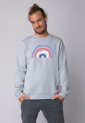 Light blue sweatshirt featuring a multi-colored rainbow graphic in red, white, and blue across the chest. Made from soft fabric.