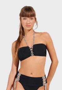 Svart bikini-set bestående av en bandeau-topp med snörningsdetalj och högmidjade underdelar med sidonlacing och märkta remmar.