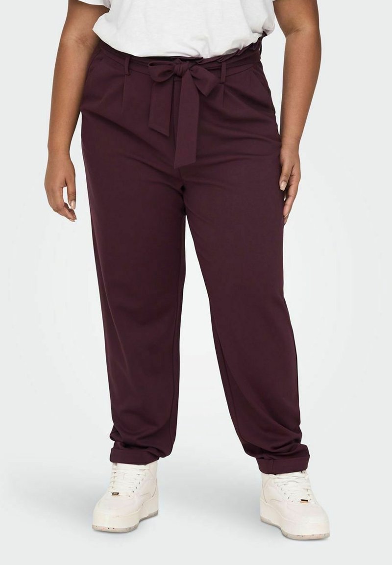 Burgundy tapered pants with a fabric belt, featuring side pockets and a smooth texture. Paired with white sneakers.
