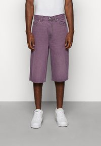Lila Denim-Shorts mit lockerer Passform, ausgestattet mit einem Fünf-Taschen-Design und einem Knopfverschluss, kombiniert mit weißen Sneakers.