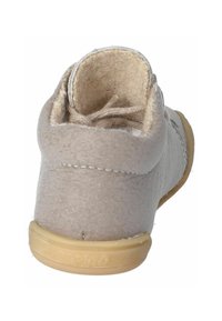 Zapato de ante gris claro con puntera redondeada, forro interior suave y suela de goma marrón. Presenta costuras beige y cierre con cordones.