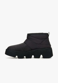 Zwarte geïsoleerde enkelboots met een gequilt bovendeel van textiel, dikke zwarte zool en een lus aan de achterkant voor eenvoudig aantrekken. Geometrisch grippatroon.