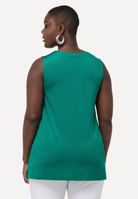 Top verde senza maniche con scollatura rotonda, caratterizzato da una texture liscia e una vestibilità rilassata, che arriva fino ai fianchi.
