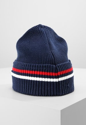 Marineblaue gestrickte Mütze mit gerippter Struktur, mit einem roten und weißen horizontalen Streifen über dem Bündchen, dargestellt auf einer weißen Oberfläche.