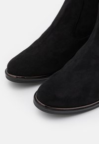 Svarta mocka ankle boots med rund tå, en slät svart sula och subtila metalliska detaljer längs sömmarna. Texturerad yta.