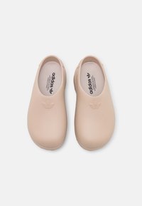 Růžové gumové nazouváky s kulatými špičkami, hladkým povrchem a minimalistickým designem. Obsahují logo Adidas a mají styl nazouvání pro snadné nošení.