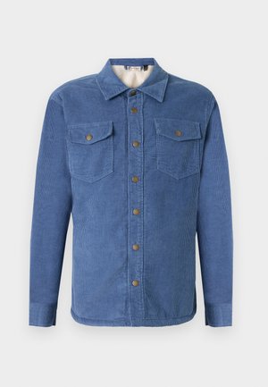 Camicetta in corduroy blu con chiusura a bottoni sul davanti, due tasche sul petto e un morbido rivestimento interno. Presenta un colletto e maniche lunghe con polsini a bottone.