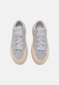 Grå semsket lær sneakers med beige gummisåle, med rundt tå, snørelukking og synlig søm på overdelen for ekstra tekstur.
