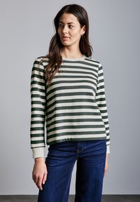 Sudadera de manga larga a rayas verdes y crema con cuello redondo y puños de canalé, combinada con pantalones de mezclilla oscuros.