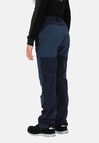 Granatowe spodnie outdoorowe z kontrastowymi, ciemnoniebieskimi panelami, zapinane na suwak boczną kieszenią i czarnymi akcentami. Wykonane z wytrzymałej, odpornej na pogodę tkaniny.