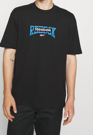 Sort t-shirt med en blå og hvid "Reebok"-logo i midten. Fremstillet af bomuld med rund halsudskæring og korte ærmer.