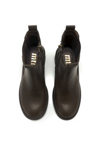 Bottines en cuir brun avec une texture lisse, fermeture éclair sur le côté et bout arrondi. Présente une semelle renforcée avec des détails de couture.