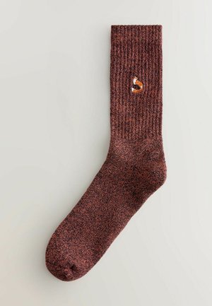 Brun ribbad strumpa med en liten broderad rävdesign. Texturen är något fluffig, med en förstärkt tå för hållbarhet.