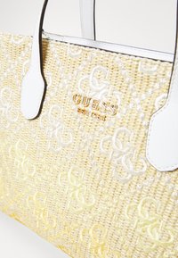 Woven straw handbag in yellow, featuring white faux leather accents and embossed logo. Textured pattern with intertwining letters throughout.