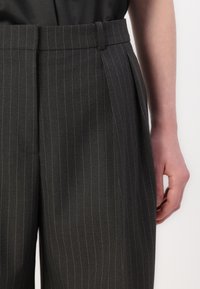 Grijze gestreepte broek met een getailleerde pasvorm, voorzien van een flat front, zijzakken en een gladde stofstructuur.