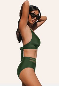 Groene bikini-set met een halternek top met een striksluiting aan de achterkant en hoge taille broekjes met doorschijnende paneelaccenten. Glad stoffen textuur.