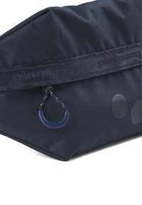 Dunkelblauer Stoffbeutel mit einer strukturierten Oberfläche, ausgestattet mit einem Reißverschluss, einem Schlaufengriff und zwei glänzenden runden Akzenten an der Seite.