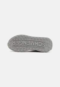 Suela de zapato de goma gris con un diseño de dibujo en forma de estrella y un logo central. Textura suave con bordes redondeados, diseñada para proporcionar tracción.