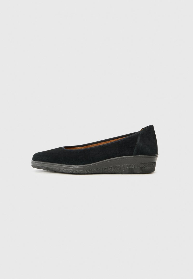 Chaussure compensée en suede noir avec un bout arrondi, semelle en caoutchouc noir texturé et un petit talon. Tige lisse avec un minimum de détails de couture.