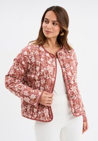 Giacca trapuntata in rosa soffice con motivi floreali in rosa e bianco. Presenta un collo rotondo e chiusura a bottoni sul davanti.