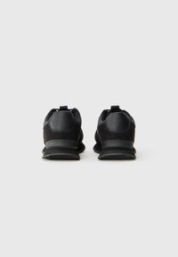 Black athletic shoes with a textured suede and synthetic upper, padded collar, and rubber sole. Features a pull tab on the heel for easy wear.