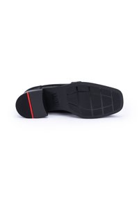 Sole di scarpa in pelle nera con un motivo testurizzato, sottile accento rosso sul tallone e una suola in gomma resistente e antiscivolo.