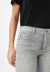 Grijze denim spijkerbroek met een aansluitend ontwerp, lichte wassing, voorkruiszakken en eenvoudige metalen details op de tailleband.