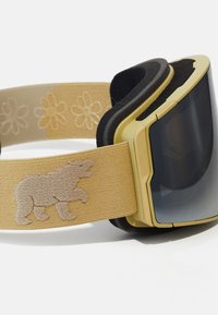 Laskettelulasit kultakehyksillä, tummilla linsseillä ja beige vyöllä, jossa on karhulogo ja kukkakuviot. Pehmeä sisäpaddedus.