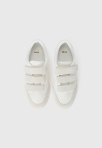 White athletic shoes with three Velcro straps, leather and suede materials, rounded toe, padded collar, and textured rubber sole.