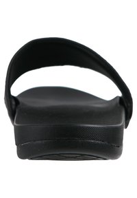 Svarta slidesandaler med platt sula, slät övre rem och texturerad fotbädd för bättre grepp. Enkel design med en lågprofilssilhuett.