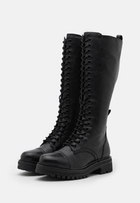 Mustat nahkaiset polvipituiset saappaat, joissa on kova pohja, täysipitkä nauhakiinnitys ja tukeva korko. Sileä pinta ja minimalistinen muotoilu.