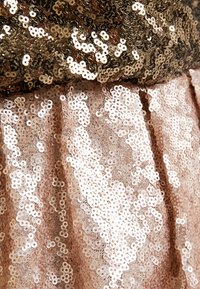 Robe sans bretelles ornée de sequins superposés en bronze et rose pâle. Texture lisse avec des embellissements circulaires brillants créant un effet scintillant.