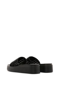 Sandali platform neri con tomaia intrecciata e accenti circolari, base solida. Progettati con suola piatta e retro aperto per un facile indossamento.