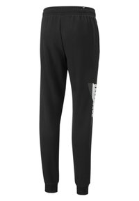 Pantalones deportivos negros con cintura elástica, piernas ajustadas y un logo gráfico blanco en el lado izquierdo; textura suave, diseño casual.