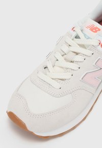 Baskets gris clair avec accents roses, en daim et tissu, bout rond, lacets blancs, semelle en caoutchouc texturée. Logo sur le côté.