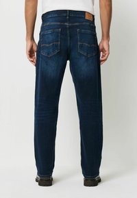 Tmavě modré džíny se střední nohavicí, s zadními kapsami a hnědou koženou nášivkou na pase. Čistý vzhled.