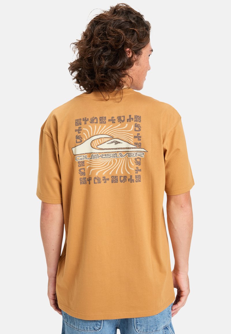 Kortærmet, ravfarvet t-shirt lavet af bomuld. Har et stort grafisk print på ryggen med buede linjer og tekst i kontrasterende farver.