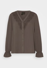 Blusa marrone con bottoni e maniche lunghe, dettagli in pizzo sul colletto e polsini frati. Tessuto morbido con superficie liscia.