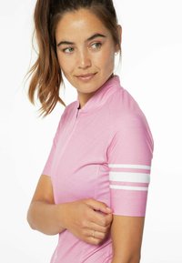 Ružový cyklistický dres s krátkymi rukávmi, s vysokým golierom a bielymi pruhmi na ľavom rukáve. Hladká textúra, športový strih.