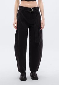 Μαύροι παντελόνες με ζώνη που διαθέτει κυκλικό μεταλλικό αγκράφα. Κατασκευασμένοι από απαλό ύφασμα, έχουν άνετη εφαρμογή και ίσια γραμμή.