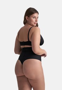 Set di reggiseno nero e slip a vita alta. Presenta spalline regolabili, texture liscia e design senza cuciture. Il tessuto appare elastico e opaco.