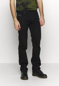Jeans di cotone neri con una vestibilità slim, caratterizzati da tasche distintive e un marchio sottile. Abbinati a stivali neri con lace-up.