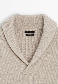 Pull en laine beige tricoté avec col châle côtelé, montrant l'étiquette de marque "Massimo Dutti" et l'étiquette du tissu à l'intérieur du col.