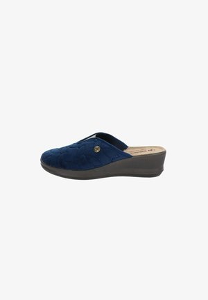 Zapatilla azul marino con textura acolchada, punta redondeada, apertura lateral y suela de cuña baja. Presenta un acento decorativo metálico.