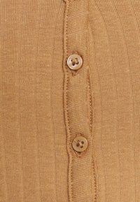 Cardigan tricoté camel avec une texture côtelée, comportant une rangée de trois boutons marron le long de la patte de boutonnage avant.