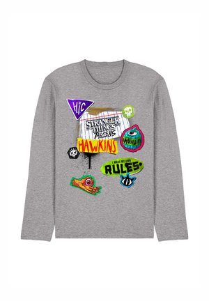 Gray long-sleeve shirt with colorful Stranger Things graphics, including "Hawkins," a purple H.I.C triangle, monster eyes, skulls, and "I make my own rules" text.