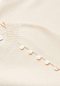 Beige Rippstrickpullover mit rundem Halsausschnitt und fünf Perlenknöpfen entlang der Knopfleiste. Weiche Textur mit subtilen Strickmustern.
