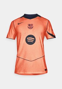 Narancssárga sportmez rövid ujjakkal, texturált anyagból, tengerészkék részletekkel, a Barcelona címerével és egy fekete Spotify logóval az elején.